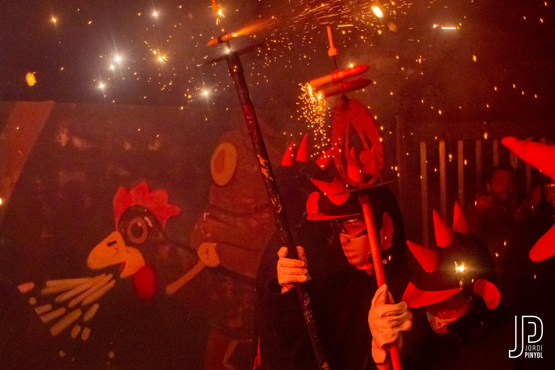Una gallina i diables amb banyes vermelles enmig del foc del correfoc