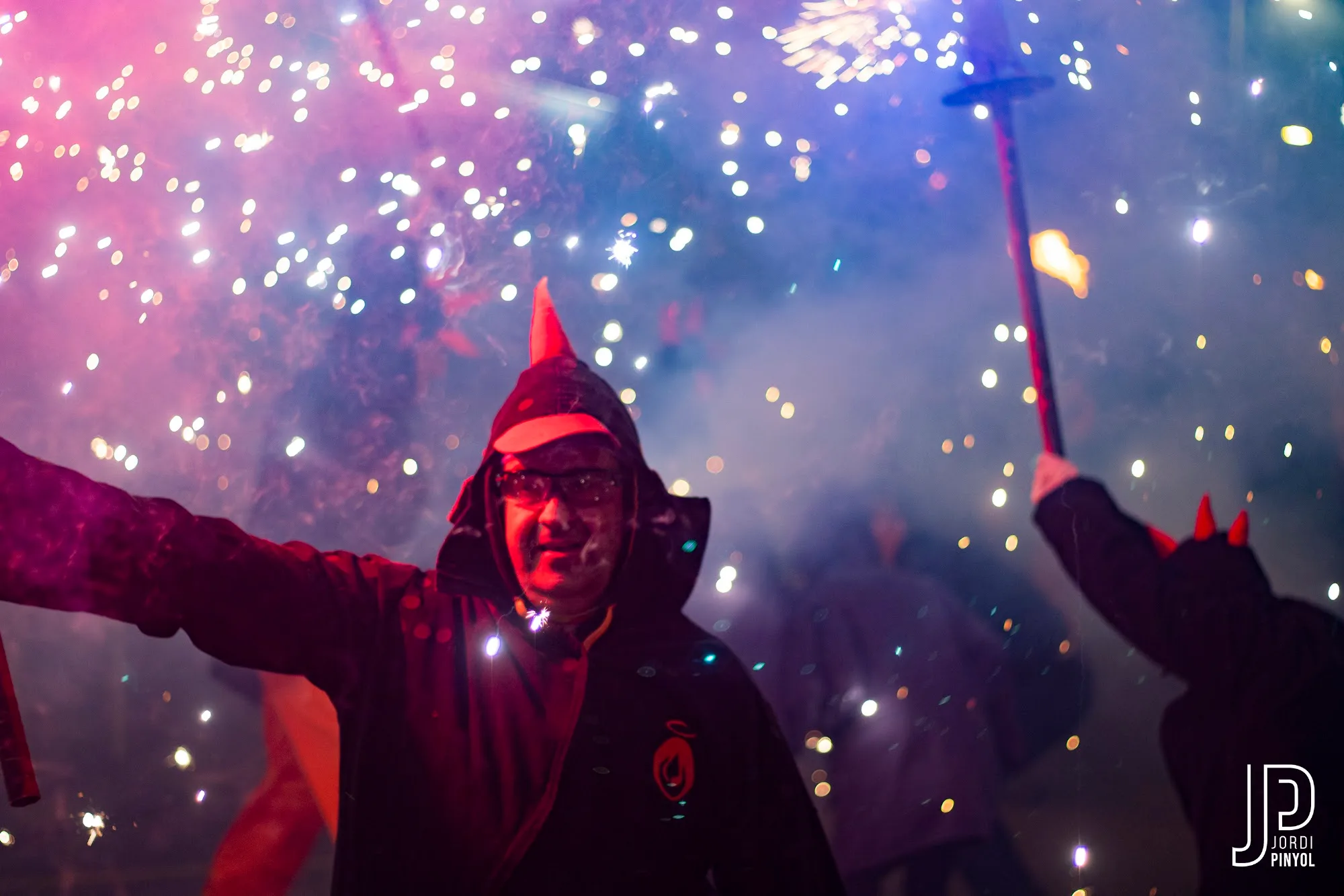Diable amb banyes vermelles saludant entre les guspires del correfoc